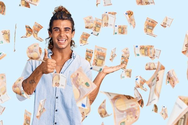Hombre contento con el pulgar levantando mientras llueven billetes de 50 euros ganados en apuestas
