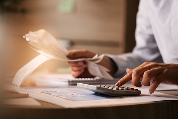 Hombre en escritorio haciendo la declaración de impuestos con una calculadora y papeles