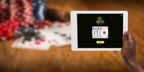 Tablet con juego de póker online y de fondo fichas y cartas de póker