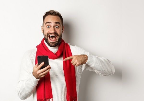 Hombre feliz señalando el móvil representando las apuestas simples