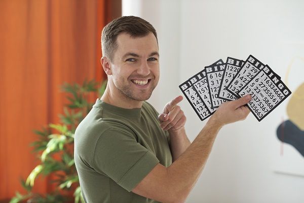 Hombre sonriendo con cartones de bingo en la mano