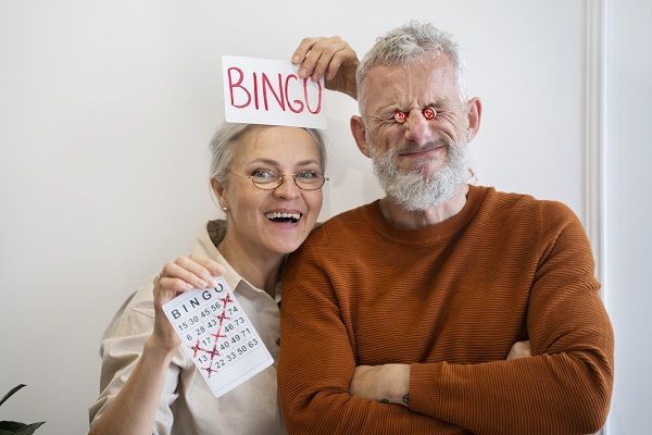Dos personas mayores con cartones de bingo y sonriendo en Francia