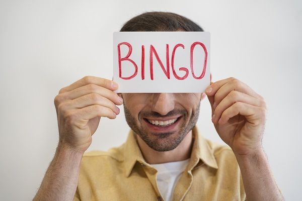 Hombre sujetando cartel con el texto bingo frente a su cara