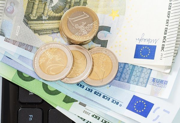 Billetes y monedas encima de un teclado representando el bankroll en inversión