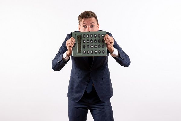 Hombre asustado detrás de calculadora representando el indicador GGR