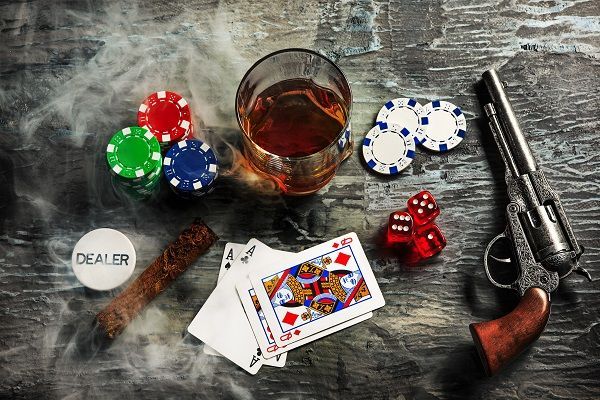 Cartas, fichas, whisky, tabaco y revolver, representando los orígenes del póker